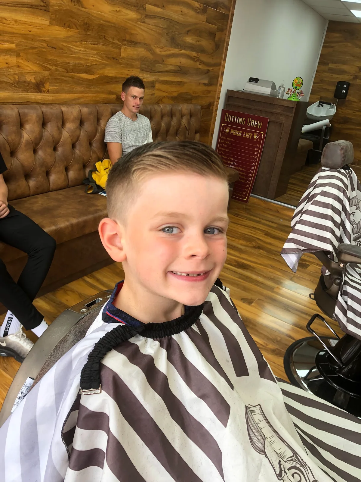 A young customer smiling after his haircut at Cutting Crew